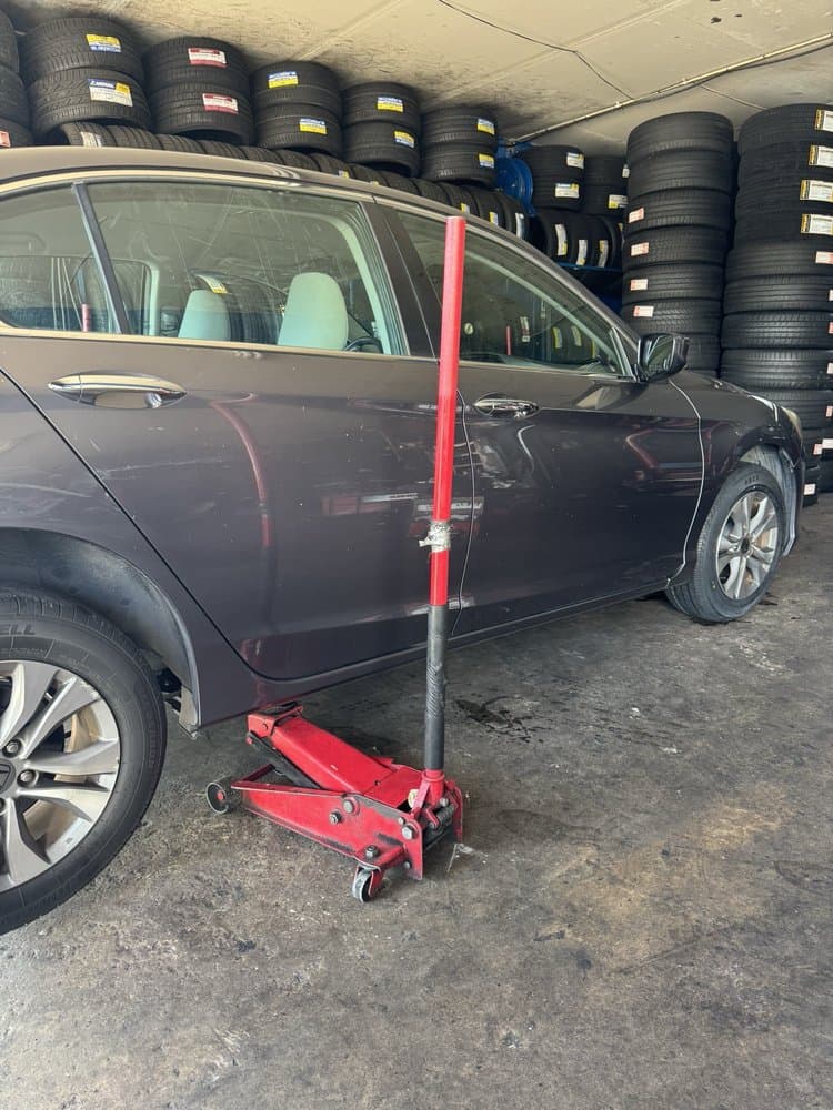 A car up on a jack stand at Quick Tire, tires stacked on shelving behind